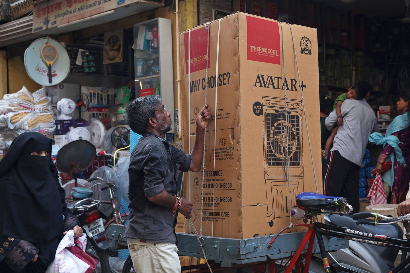 Sykkelen brukes også til få levert større og tynge varer. Her er en syklist i ferd med å forberede transporten av en luftkjøler i Varanesi i India.